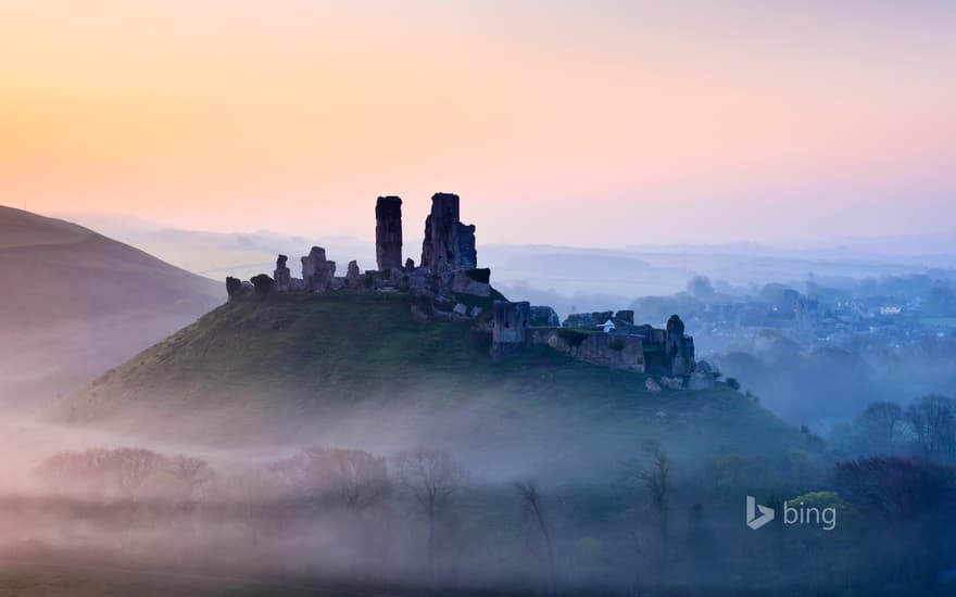 Corfe Castle shrouded in mist at sunrise in Dorset, England